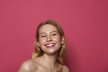 Happy smiling blonde woman isolated on pink