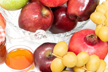 Rosh Hashanah (Jewish New Year) Traditional Symbols, Honey in a glass jar, Pomegranates, Dates, Red And Green Apples. Isolated On A White Background