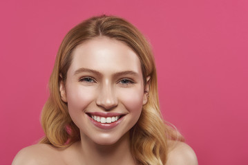 Sincere smiling blonde woman isolated on pink