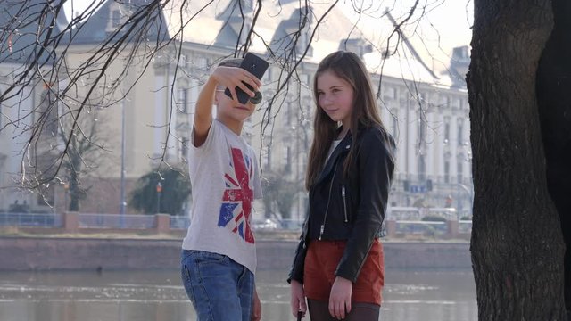 Teenager young friends walk in a city taking selfie pictures via smartphone by a river water in park in Wroclaw Poland