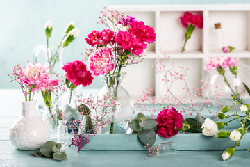 Bouquet of pink carnation in glass vase on light turquoise wooden background. Mothers day, birthday greeting card.