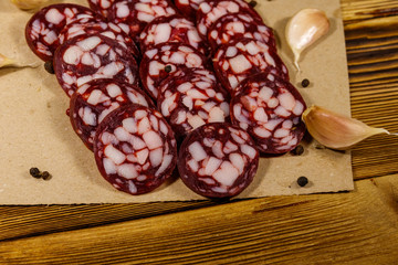 Sliced salami sausage on brown paper on wooden table