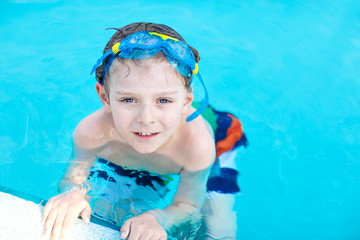 little preschool kid boy making swim competition sport. Kid with swimming goggles reaching edge of the pool . Child having fun in an swimming pool. Active happy child winning. sports, active leisure.