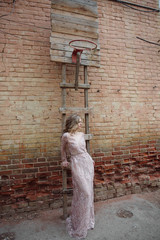Young woman in a long pink dress with lace posing on the street