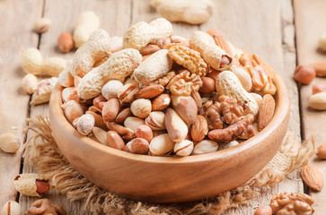 Nuts set assortment in bowl with almonds, pistachios, cashews, hazelnuts, peanuts, Brazil nuts, walnuts, vintage wooden kitchen table background