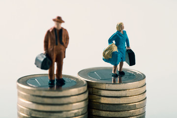 miniature man and woman on two piles of coins