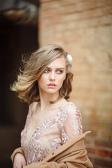 Closeup portrait of a beautiful young blonde woman with a hairdress and make-up in a dress
