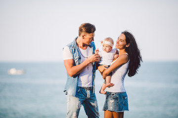 family outdoor recreation with sea views. young Caucasian family with one year old child in arms,...