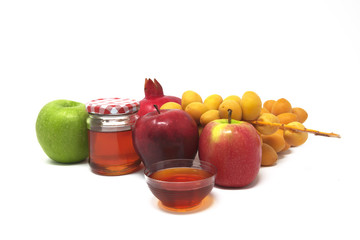 Rosh Hashanah (Jewish New Year) Traditional Symbols, Honey in a glass jar, Pomegranates, Dates, Red And Green Apples. Isolated On A White Background