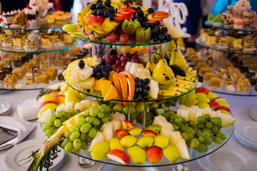 Exotic, organic fruits, light snacks in a plate on a buffet table. Assorted mini delicacies and snacks. Decorated delicious table for a party goodies