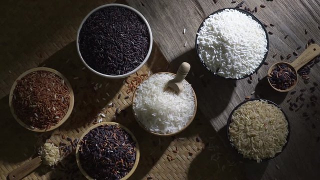 Organic brown rice and asian black riceberry with jasmine white rice in bowl on wooden desk, uncooked products by organic natural food concept, top view
