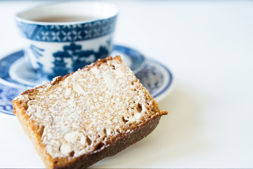 close up typical Dutch spiced caked called ontbijtkoek or peperkoek, with cup of tea. Against white background