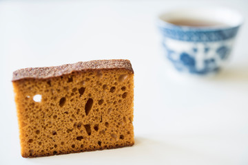 close up typical Dutch spiced caked called ontbijtkoek or peperkoek, with cup of tea. Against white background