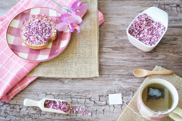 decorative flat lay, Dutch breakfast with cup of tea, rusk with pink sweet sprinkles, hail on plate on wooden table