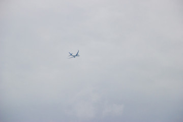 Distant airplane flying in the cloudy sky
