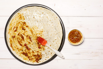 Put passata with a brush. recipe step by step pizza capricciosa flatlay on white wood