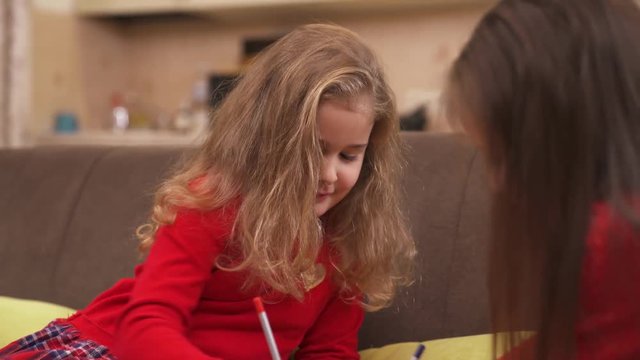 Charming little girls are drawing with colored pencils