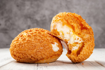 two pieces sweet puffs and one with a bite on a white wood table