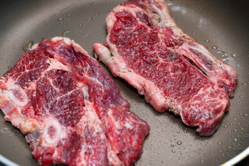 frying two pieces steaks on a pan at home