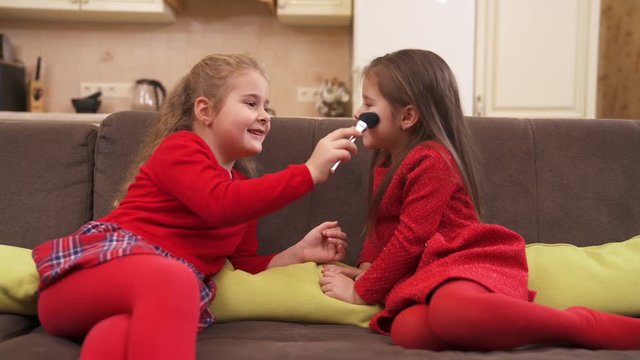 Little girl plays with a makeup brush and imagines how she is doing makeup to her friend