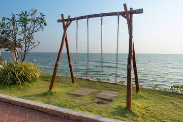 Fototapeta premium Swing in the garden beside the ocean and clear blue sky