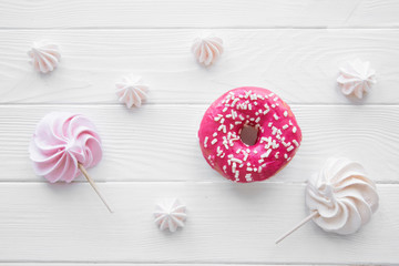 Pink doughnuts and pink and white meringue sweets background. Bright colors. 