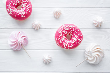 Tasty doughnuts and pink and white delicious meringues on white background. 