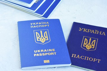 Internal passport of Ukraine with a state emblem trident and stack of biometric documents for international travel with personal id data. Passport of a citizen of Ukraine and stack of id passports 