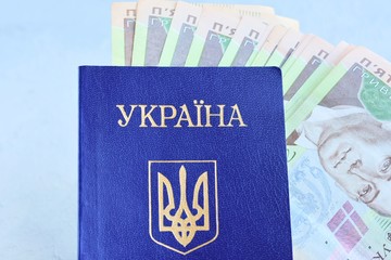 Internal passport of Ukraine with the national currency hryvnia inside on neutral background. Passport of a citizen of Ukraine with a state emblem trident on the blue cover and money inside 