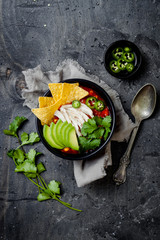 Chicken tortilla chili soup with nachos, avocado, lime, jalapeno. Mexican traditional dish