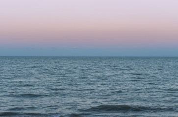 Purple sea and beautiful sky over the sea during sunset with small water ripples.