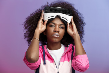Mod curly brown-haired girl dressed in the pink sports jacket wearing on her head the virtual...