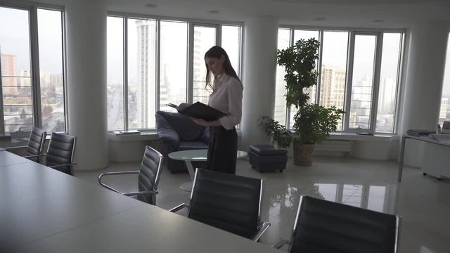 business woman walking through an empty office with a folder for papers. woman working alone in the evening
