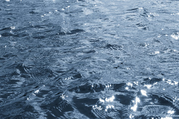 Background, texture from dark waves, in which the sun reflects. Dark waves on the surface of the...