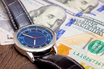 The watch is lying on dollars. Time to earn money. Time is money_