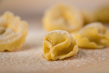 Frische, rohe Cappelletti Tortellini Pasta mit Mehl und Grieß auf Holz Brett