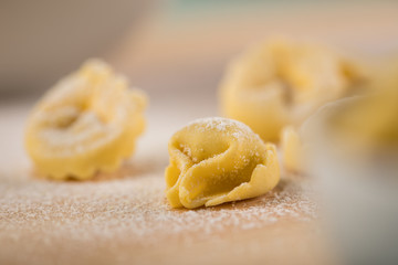 Frische, rohe Cappelletti Tortellini Pasta mit Mehl und Grieß auf Holz Brett