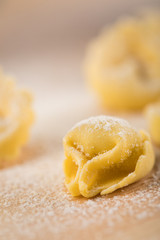 Frische, rohe Cappelletti Tortellini Pasta mit Mehl und Grieß auf Holz Brett