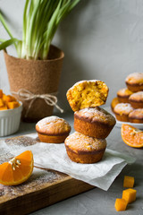 vegan dessert. sweet homemade muffins with pumpkin and orange and powdered sugar on a grey background. copy space. selective focus