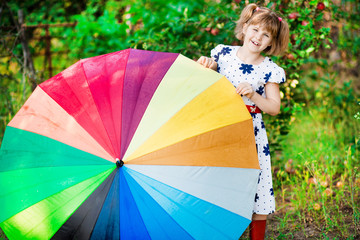 Happy child girl walk with multicolored umbrella under rain