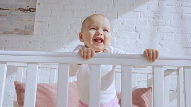 adorable smiling toddler child in baby crib throwing toy 