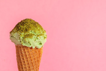 creative concept with unstable pistachio ice cream cone strewed nuts on pink background