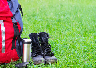 Hiking travel gear on glasses. Items include hiking boots, cup, map, binoculars. Flat lay of outdoor travel equipment items for mountain camping trip.