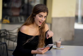 Attractive young woman checking mobile phone happy having lots of followers on her online blog