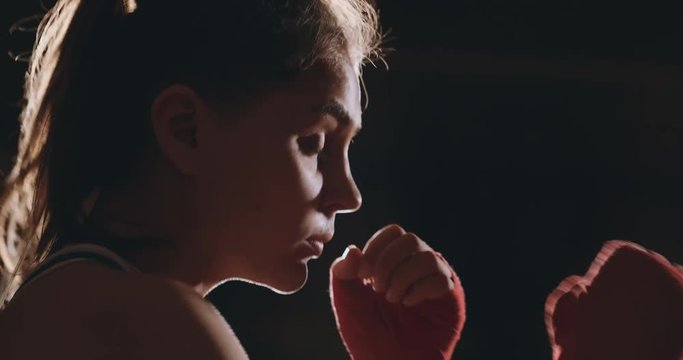 A strong athletic, woman boxer, boxing at training on the black background. Sport boxing Concept with copy space.