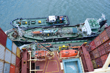 Container ship is taking fuel during port stay. Two barges are moored together and pumping fuel in same time.