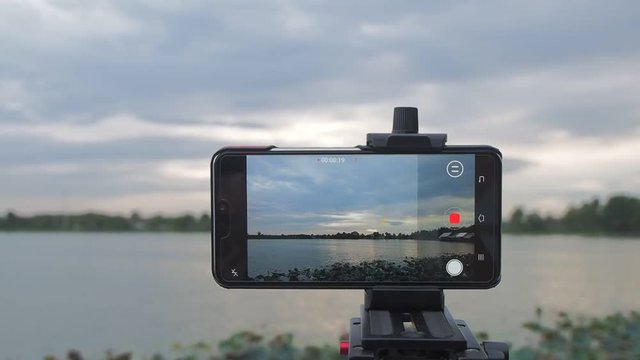 view of android smart phone recording VDO4K and shooting timelapse with rain storm anc dark clouds moving show on monitor, Krajub reservoir, Banpong, Ratchaburi, Thailand.