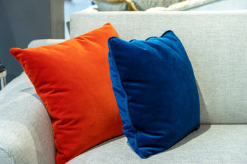 Orange and blue decorative pillows on a beige sofa.