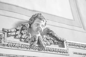 Closeup of an architectural detail. Bas-relief of a cherub with wings, enriched with stucco...