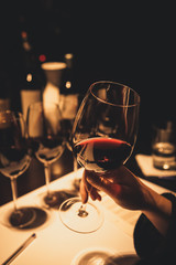 Woman holding glass of red wine during a wine tasting event. - obrazy, fototapety, plakaty